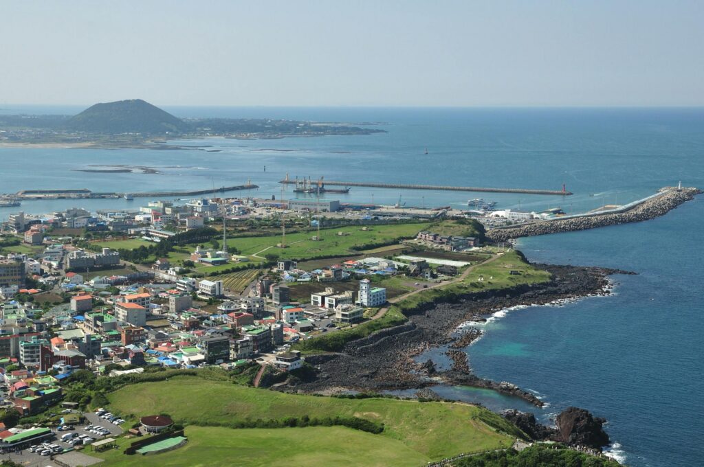 A scenic aerial shot capturing the vibrant coastal town and landscape of Jeju Island in South Korea.